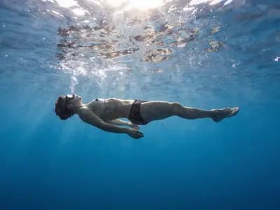 A freediver floating face down and relaxed at the surface