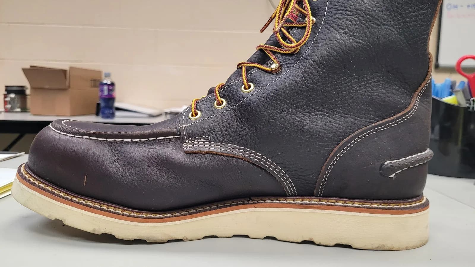 A leather work boot photographed from the side, the row of welt stitching visible along the ledge where the upper meets the sole