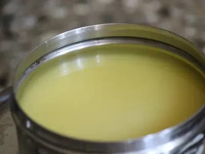Homemade ghee cooling in a steel pot, clear and deep gold, with the browned milk solids already strained out