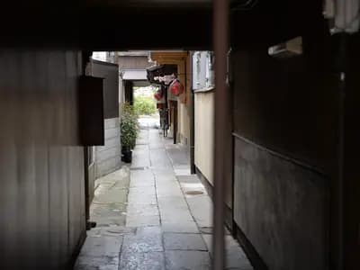 Crowds of tourists walking through a narrow historic street in Kyoto lined with traditional wooden buildings