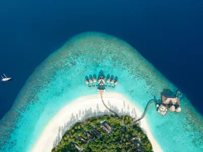 An aerial view of a Maldives atoll reef and lagoon with a dive boat anchored offshore
