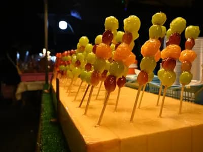 A row of glossy, sugar-glazed candied strawberry skewers with a hard, cracked candy shell, tanghulu style
