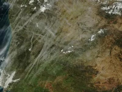A weather research aircraft flying beneath rain clouds over an arid landscape