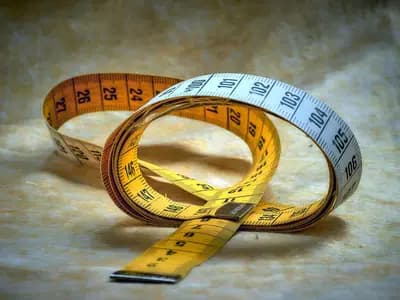 A tailor's cloth tape measure coiled on a table, marked in centimetres and inches