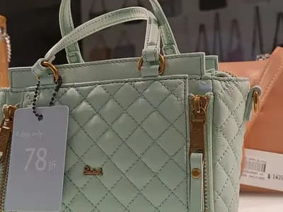 Handbags in a shop window carrying discount tags and price tickets