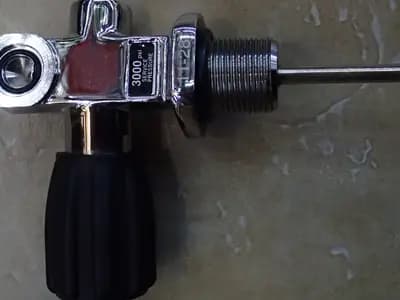 A scuba cylinder valve in close up, showing the threaded outlet, the handwheel and the pressure rating stamped into the body