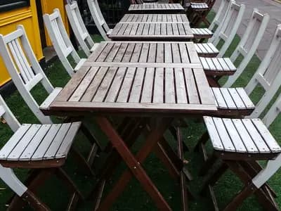 Empty wooden tables and chairs set out on the pavement outside a cafe
