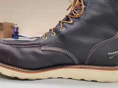A leather work boot photographed from the side, the row of welt stitching visible along the ledge where the upper meets the sole