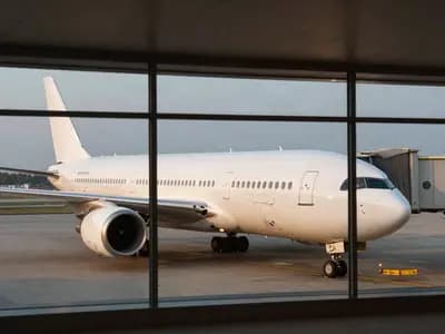 An aircraft seen through an airport terminal window in the evening