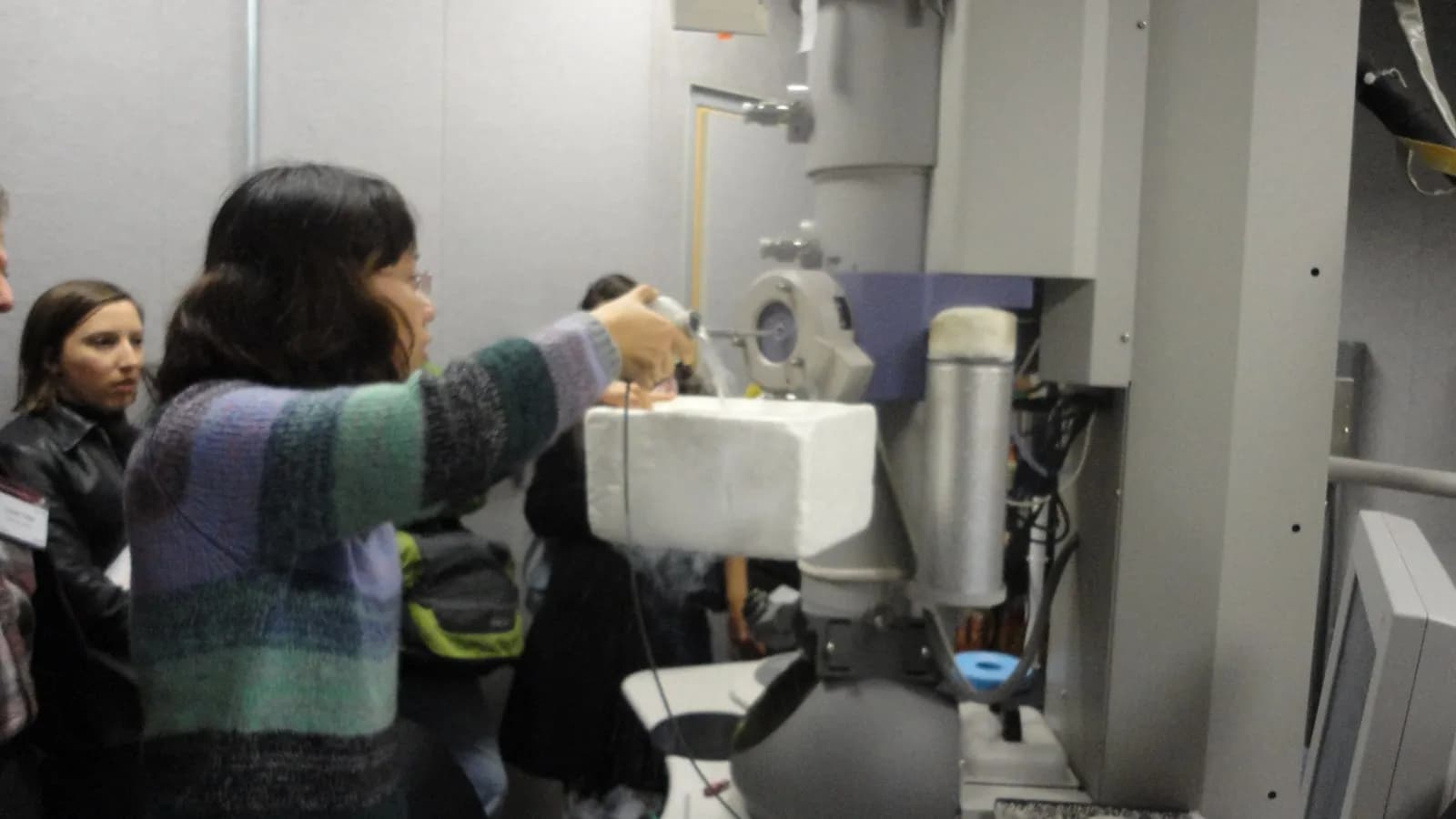 Researchers loading a sample into a cryo-electron microscope, the instrument the UC San Diego team used to image the enzyme at work