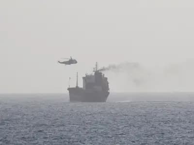 A merchant tanker under way in the Arabian Gulf while a helicopter lowers a boarding party onto its deck. The photograph records the boarding of the MT Wila in August 2020 and is not from the current closure