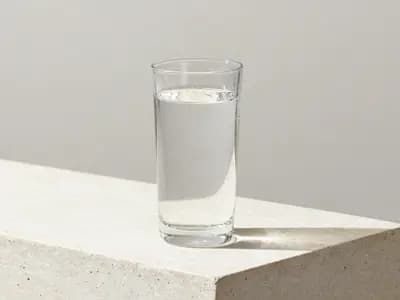 A glass of water with condensation on a stone counter