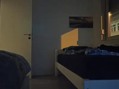 A dark bedroom at night with a street light shining through the window onto the bed, the kind of low light the study measured
