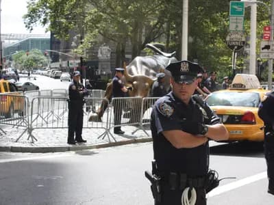The Charging Bull sculpture on Broadway near Wall Street in New York, with pedestrians passing behind it