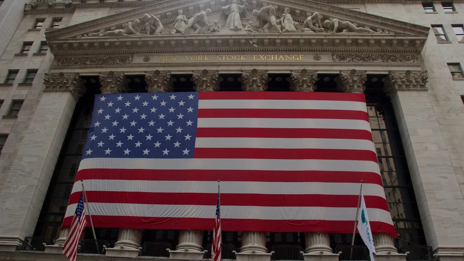The New York Stock Exchange facade on Wall Street with a large American flag, photographed in July 2012