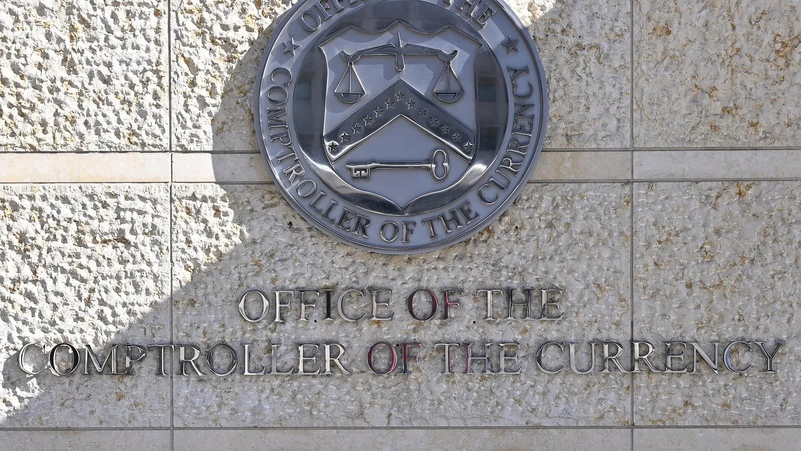 The seal and lettering of the Office of the Comptroller of the Currency on a stone wall outside its headquarters at 400 7th Street SW in Washington, photographed on 10 February 2025, a file photograph of the agency's sign and not of the rule's release