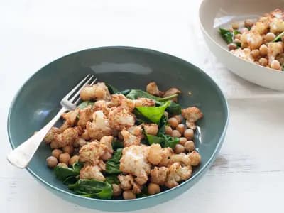 A wooden table with bowls of legumes, tofu, nuts and grilled protein representing plant and animal protein sources