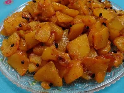 Pumpkin curry, kaddu ki sabzi, served on a glass plate with whole spices visible among the softened cubes