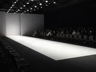 A lit empty runway with the audience seated on either side before a show