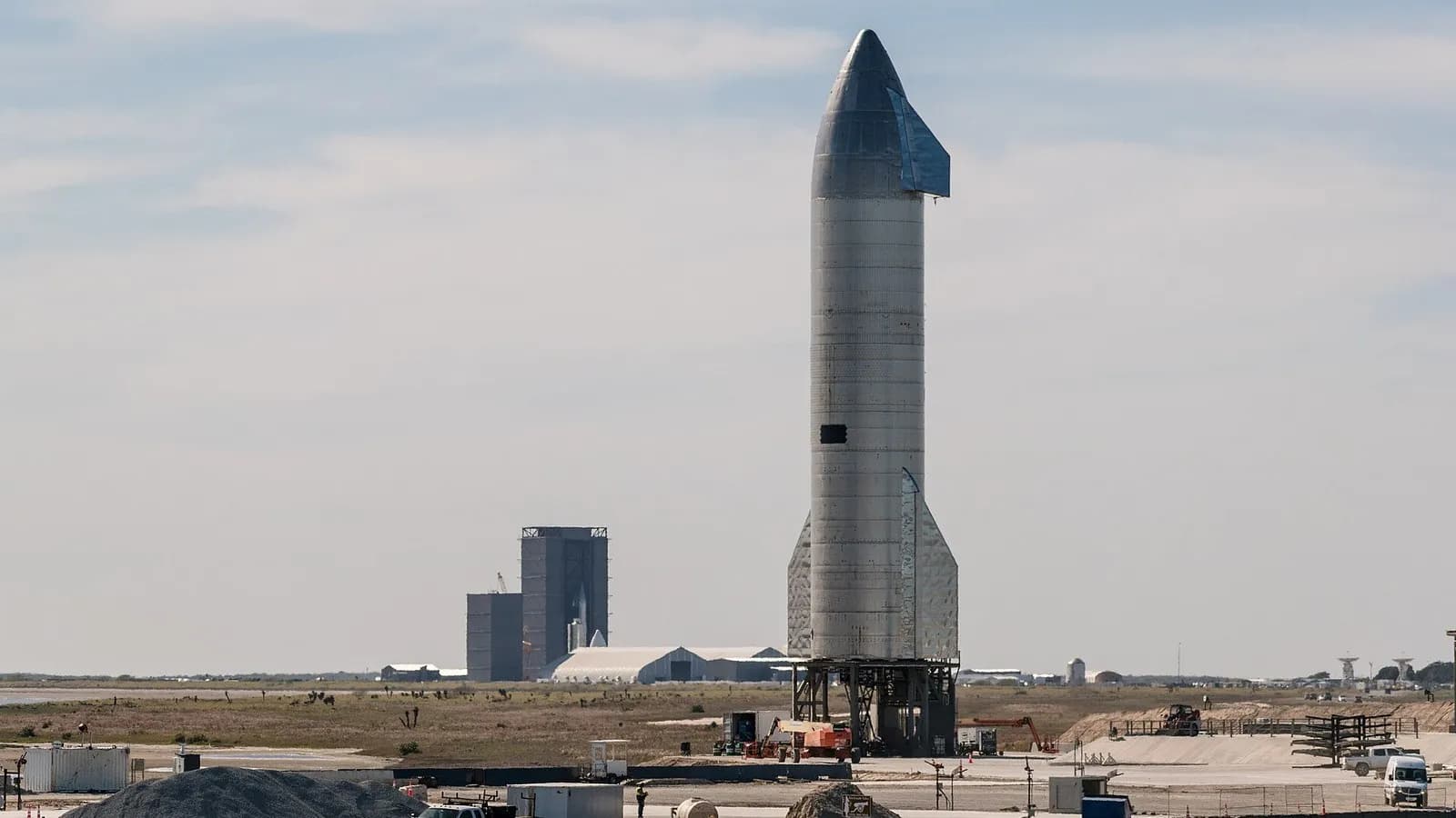 A stainless-steel Starship prototype standing on its launch mount at SpaceX's Starbase site in Texas with the build site behind it, photographed on 16 January 2021, a file photograph of SpaceX hardware and not from this week's earnings call