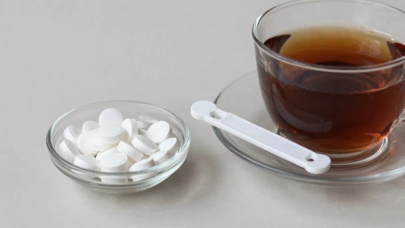 Sweetener tablets and a dispenser beside a cup of tea