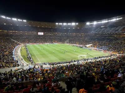 A packed stadium crowd at a World Cup match with fans in team colors under stadium lights