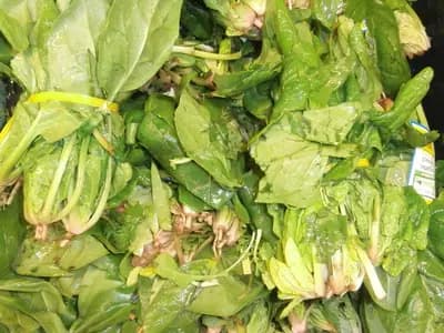 Bunches of fresh spinach stacked in a market crate