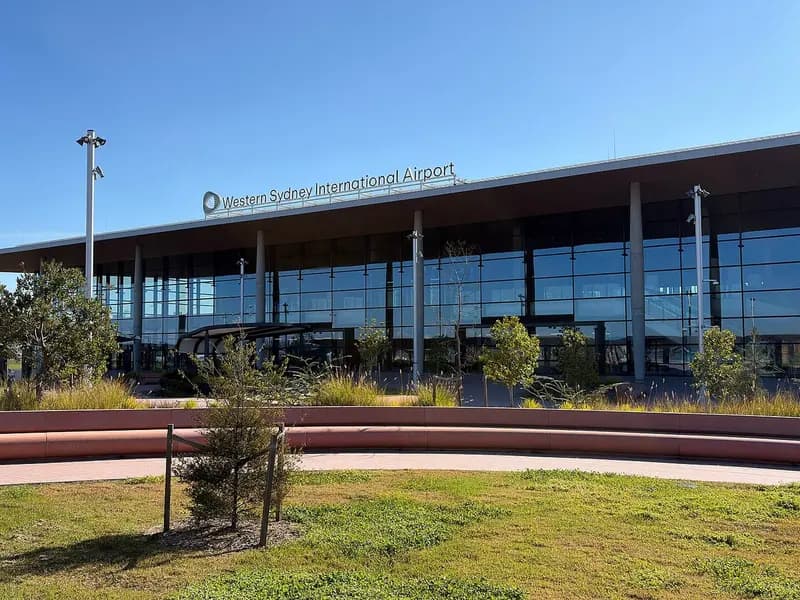 The glass-fronted terminal building of Western Sydney International Airport under a blue sky, with its name above the entrance, photographed in July 2026, a file photograph of the terminal before the first passenger flights